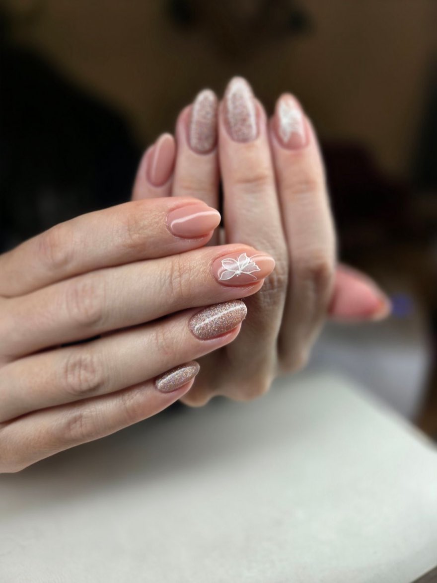 Gepflegte Nude-Maniküre mit feinem Glitzer und Blütendesign